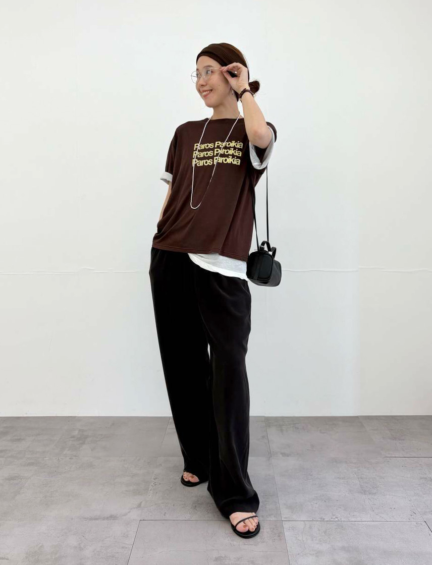 茶色ロゴTシャツと黒色スラックスのコーディネート